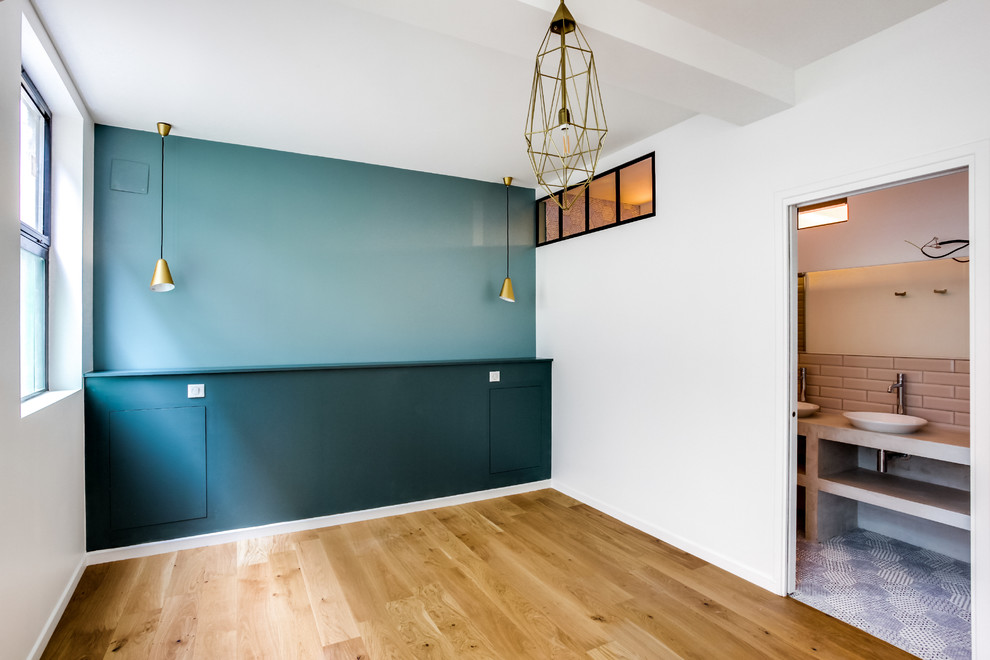 Imagen de dormitorio principal industrial grande sin chimenea con paredes azules, suelo de madera clara y suelo marrón
