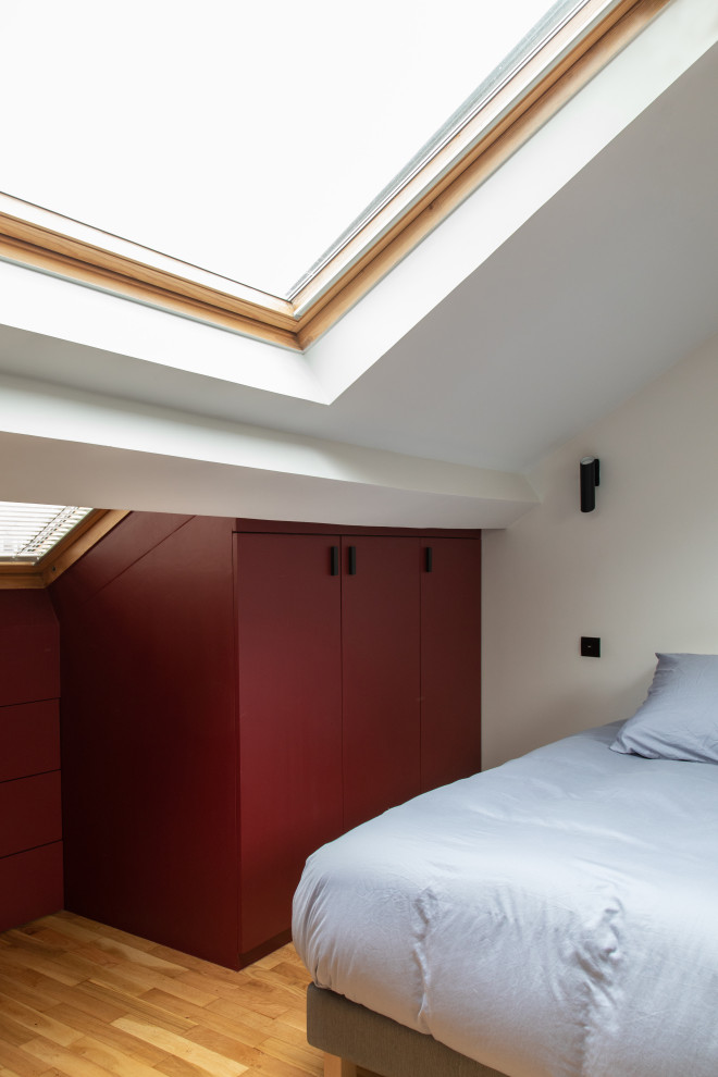 Diseño de dormitorio urbano de tamaño medio con paredes rojas y suelo de madera clara
