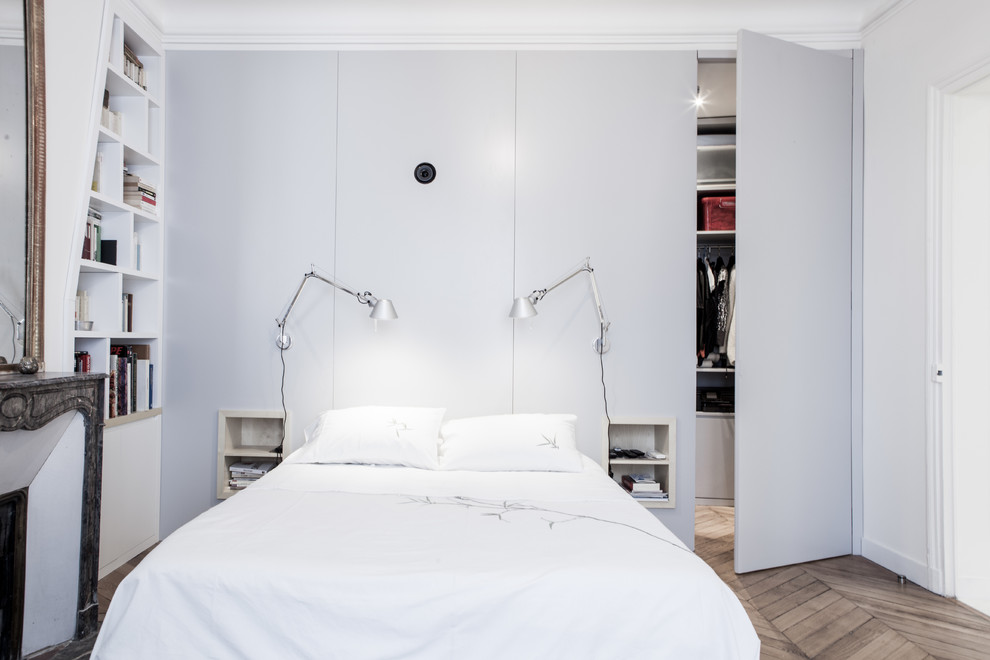 Mittelgroßes Modernes Hauptschlafzimmer mit grauer Wandfarbe, braunem Holzboden, Kamin und Kaminumrandung aus Stein in Paris
