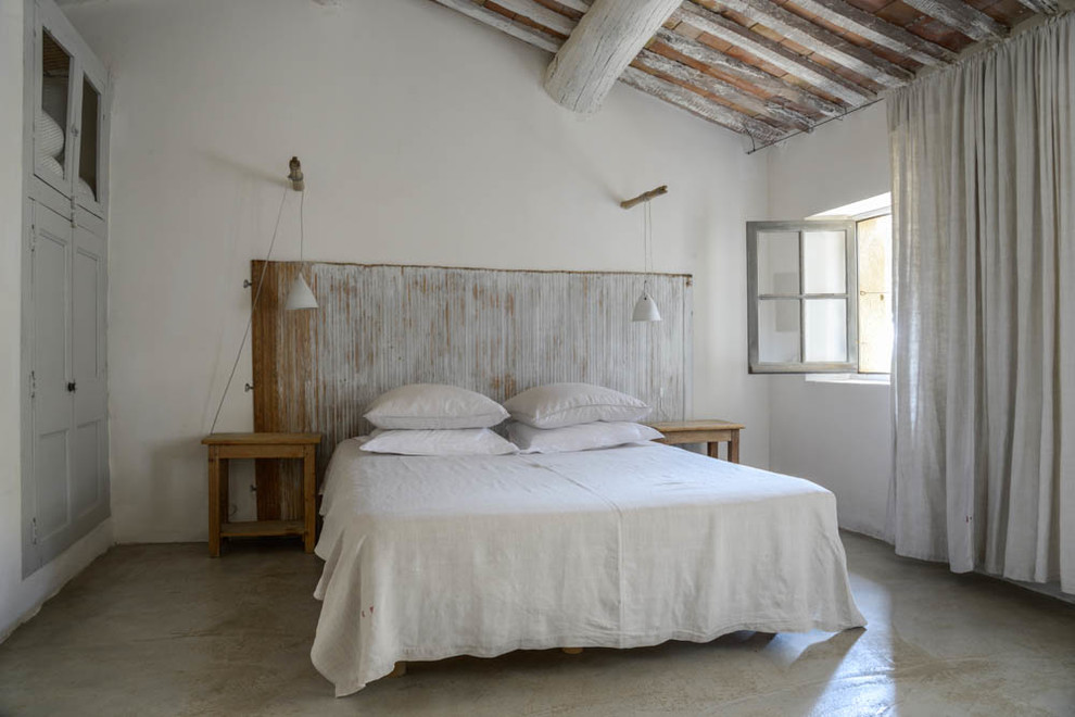 Imagen de habitación de invitados campestre de tamaño medio sin chimenea con paredes blancas y suelo de cemento