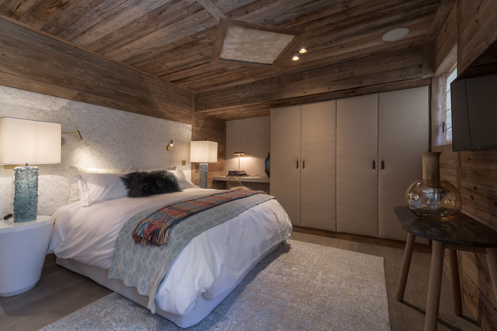 Ejemplo de dormitorio principal rural grande con paredes blancas, suelo de madera en tonos medios y suelo marrón