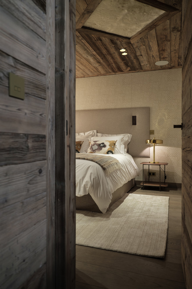 Idée de décoration pour une grande chambre d'amis chalet avec un mur beige, un sol en bois brun et un sol marron.