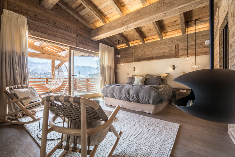 Esempio di una grande camera matrimoniale rustica con pareti beige, pavimento in legno massello medio, camino sospeso e cornice del camino in metallo