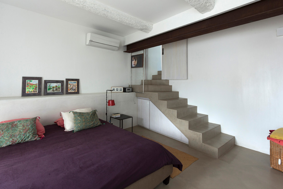 Esempio di una camera degli ospiti contemporanea di medie dimensioni con pareti bianche e pavimento in cemento