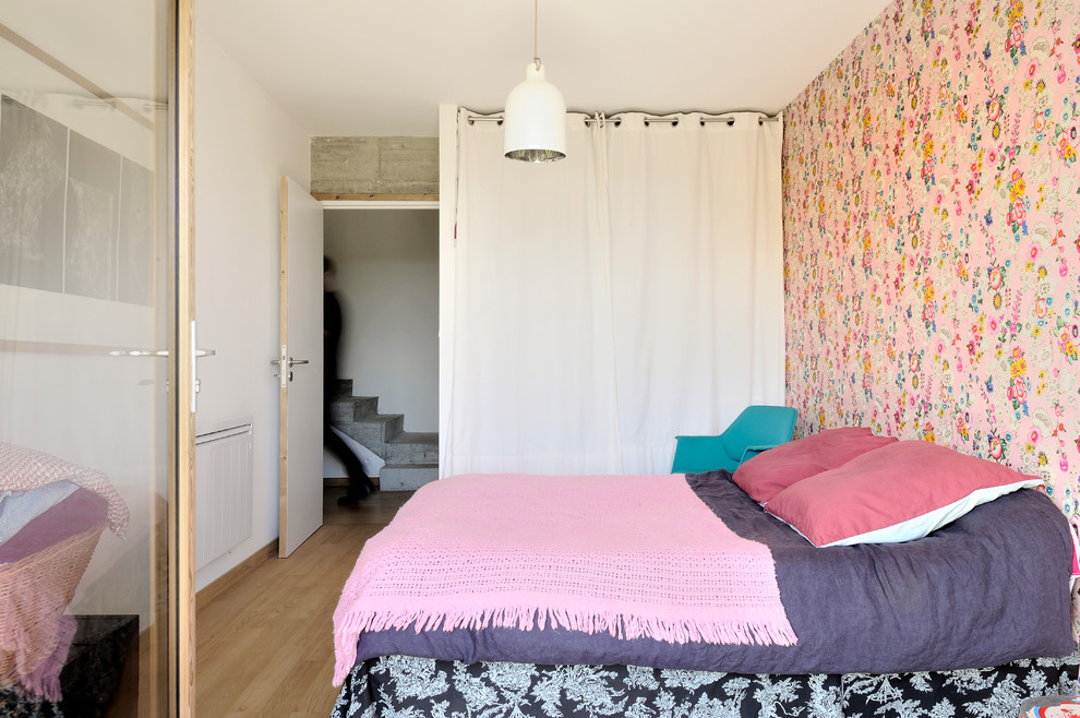 Cette image montre une chambre parentale design de taille moyenne avec un mur multicolore et un sol en bois brun.