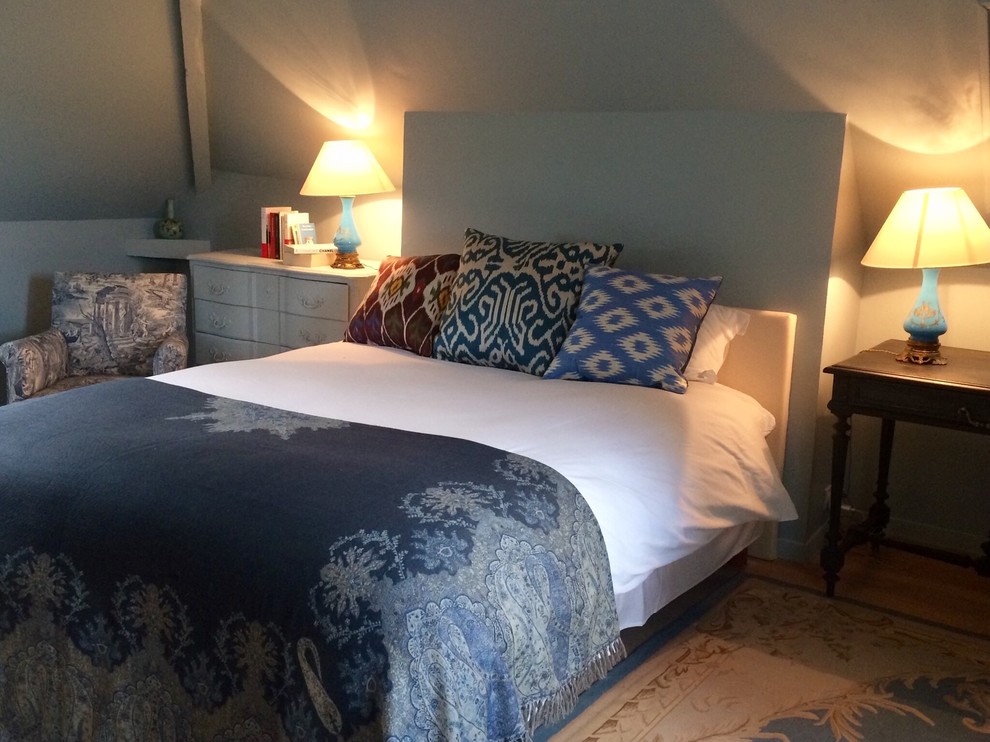 Ejemplo de habitación de invitados de estilo de casa de campo de tamaño medio sin chimenea con paredes azules, suelo de madera clara y suelo beige