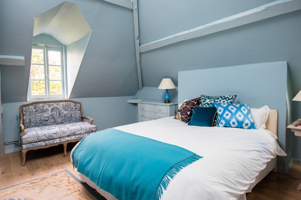 Foto de habitación de invitados de estilo de casa de campo de tamaño medio sin chimenea con paredes azules, suelo de madera clara y suelo beige