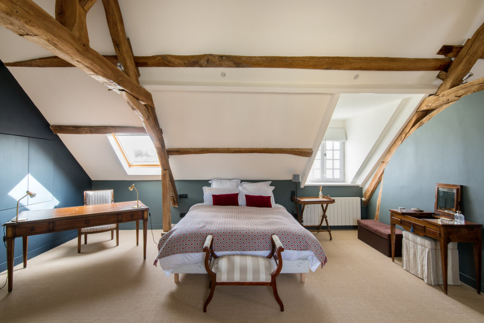Modelo de dormitorio abovedado de estilo de casa de campo con paredes azules, moqueta, suelo beige y vigas vistas