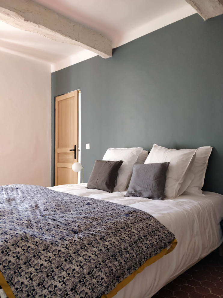 Diseño de habitación de invitados mediterránea de tamaño medio sin chimenea con paredes grises, suelo de baldosas de terracota, suelo rojo y vigas vistas