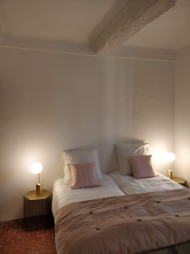 Diseño de habitación de invitados mediterránea de tamaño medio sin chimenea con paredes blancas, suelo de baldosas de terracota, suelo rojo y vigas vistas