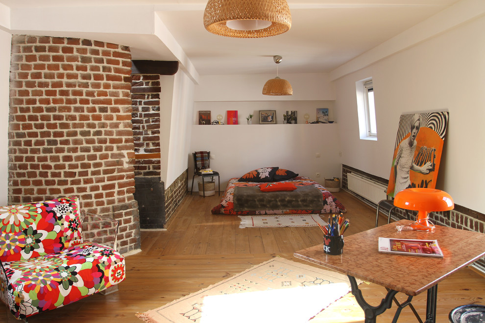Cette photo montre une chambre parentale éclectique de taille moyenne avec un mur blanc, un sol en bois brun et un sol marron.