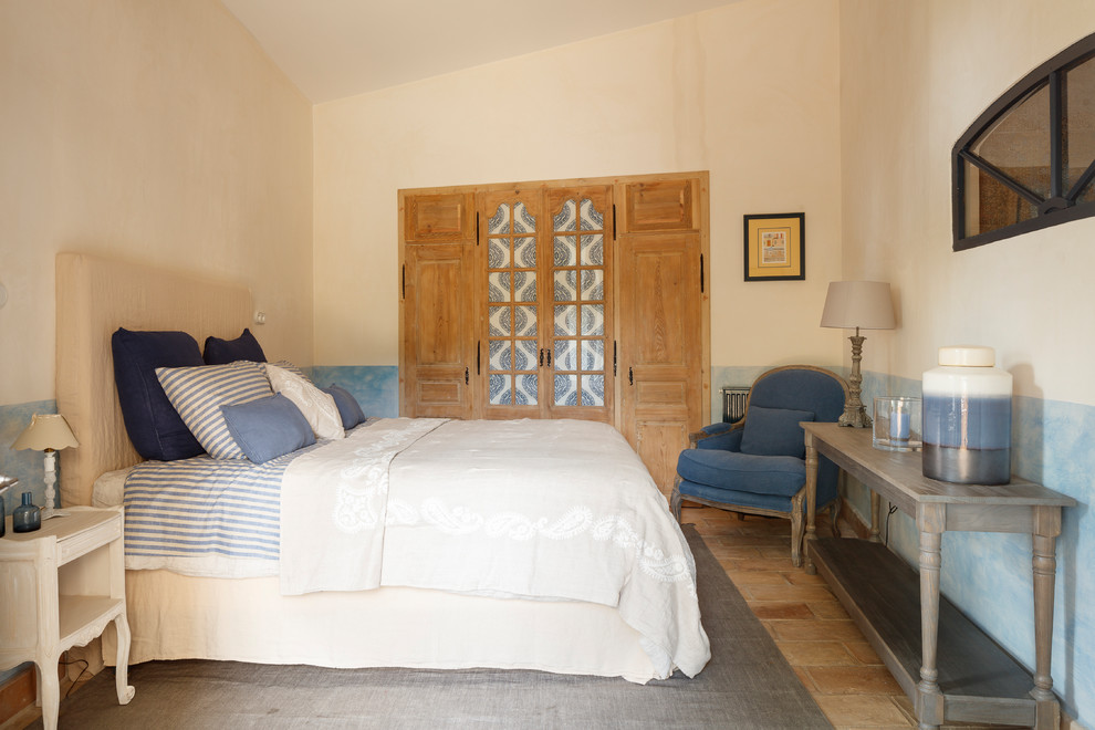 Cette image montre une chambre d'amis méditerranéenne de taille moyenne avec un mur bleu et un sol beige.
