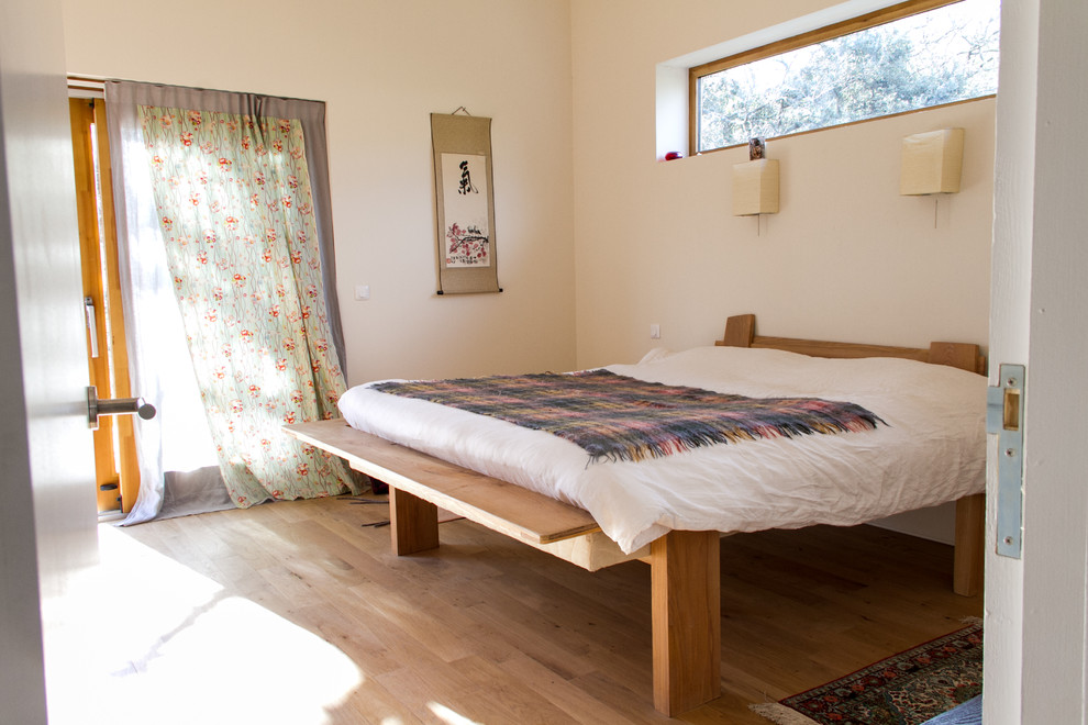 Imagen de dormitorio principal bohemio de tamaño medio sin chimenea con paredes blancas y suelo de madera clara