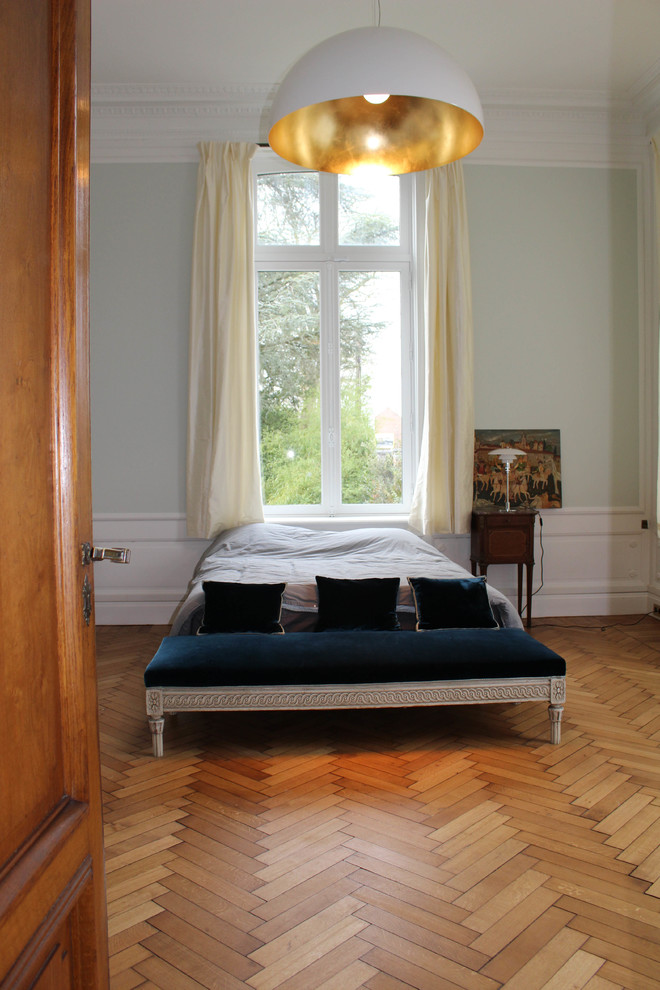 Klassisk inredning av ett stort sovrum, med blå väggar, ljust trägolv, en standard öppen spis, en spiselkrans i sten och brunt golv