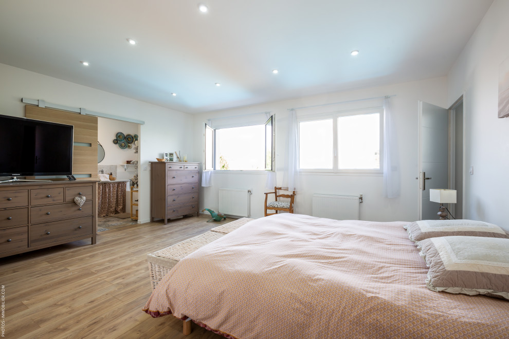 Foto de dormitorio principal actual grande con paredes blancas, suelo de madera en tonos medios y suelo beige