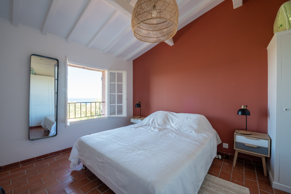 Imagen de dormitorio principal mediterráneo grande con paredes rojas, suelo de baldosas de terracota y suelo rojo
