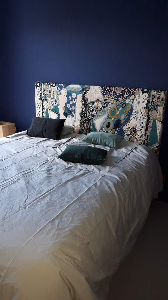 Réalisation d'une chambre parentale bohème de taille moyenne avec un mur bleu et sol en béton ciré.