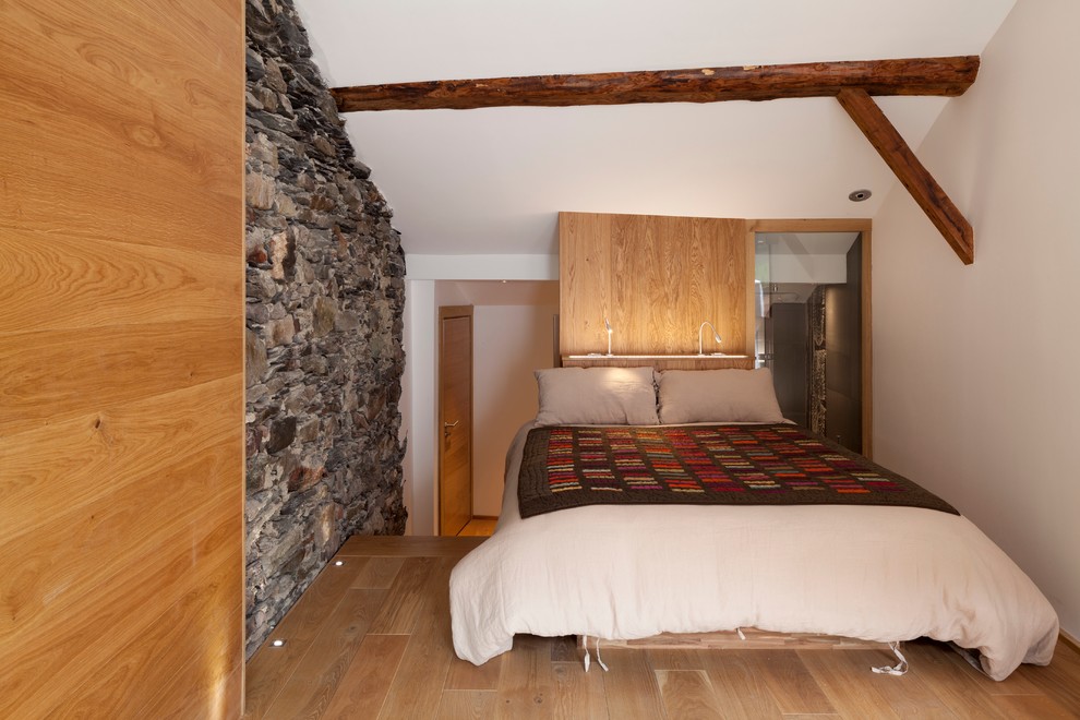 Foto på ett litet rustikt sovloft, med vita väggar och mellanmörkt trägolv