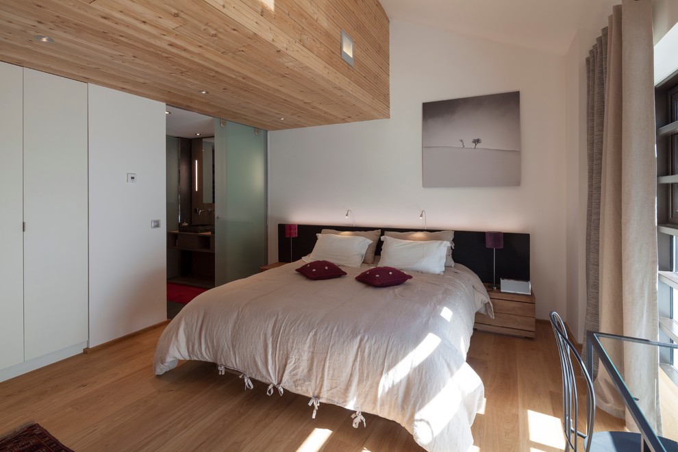 Idee per una camera matrimoniale contemporanea di medie dimensioni con pareti bianche e pavimento in legno massello medio