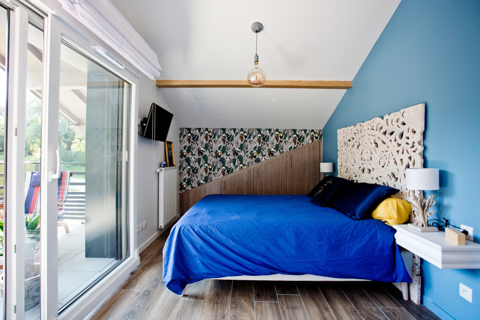 Aménagement d'une grande chambre parentale montagne avec un mur bleu, un sol en bois brun, aucune cheminée et un sol marron.