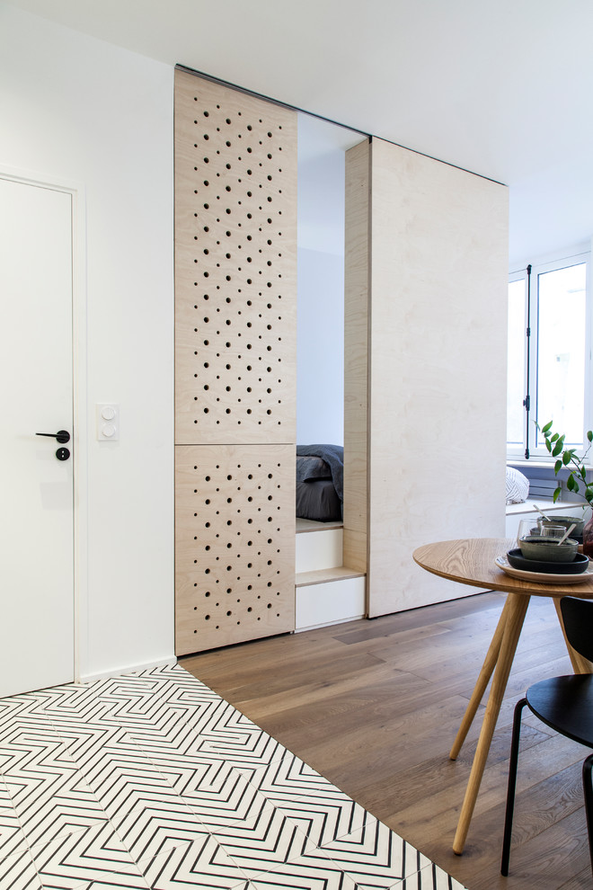 Mittelgroßes Nordisches Hauptschlafzimmer ohne Kamin mit weißer Wandfarbe, hellem Holzboden, beigem Boden und Holzwänden in Paris
