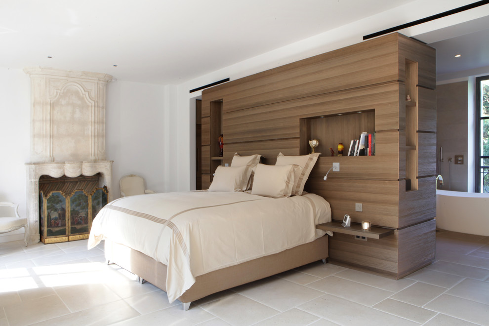 Idée de décoration pour une chambre parentale design avec un mur blanc, une cheminée standard et un sol gris.