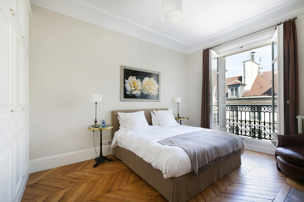 Exemple d'une chambre d'amis chic de taille moyenne avec un mur beige et un sol en bois brun.