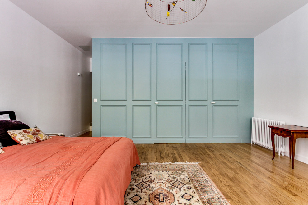 Cette photo montre une chambre chic avec un mur bleu, parquet clair et un sol beige.