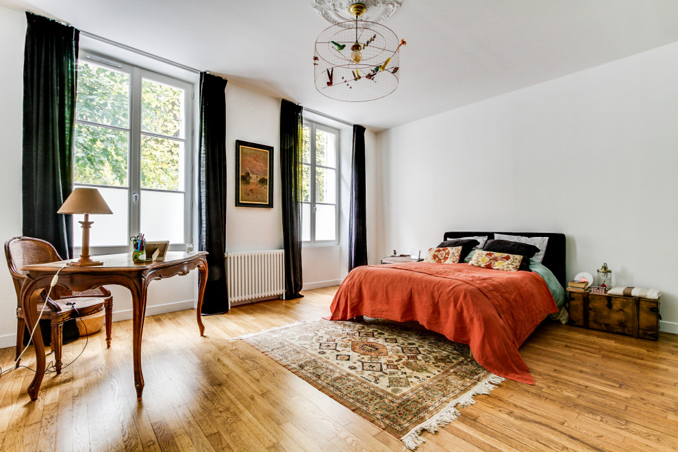 Idée de décoration pour une chambre design avec un mur blanc, un sol en bois brun et un sol marron.
