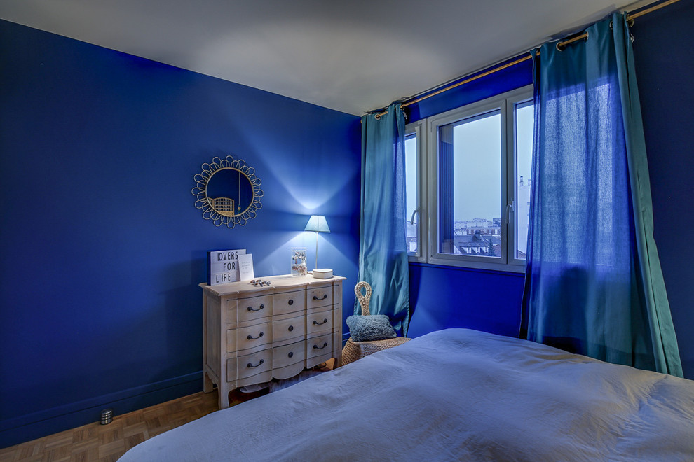 Ejemplo de dormitorio principal nórdico de tamaño medio con paredes azules y suelo de madera clara