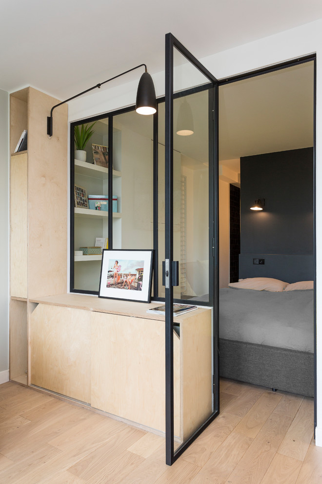 Imagen de dormitorio principal minimalista de tamaño medio sin chimenea con paredes blancas, suelo de madera clara y suelo beige