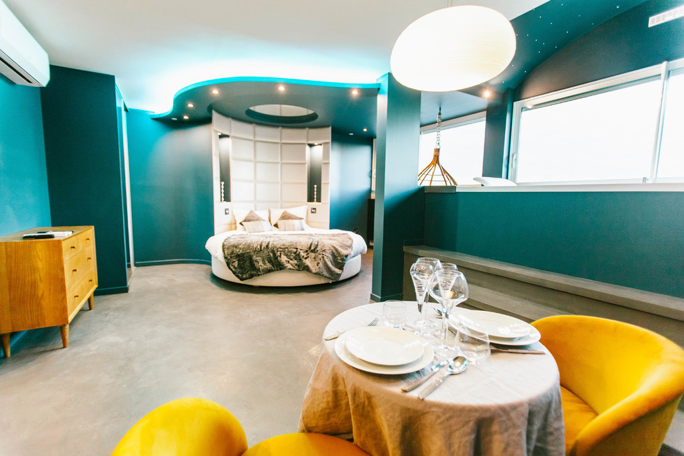 Immagine di una grande camera matrimoniale design con pareti blu, pavimento in cemento e pavimento grigio
