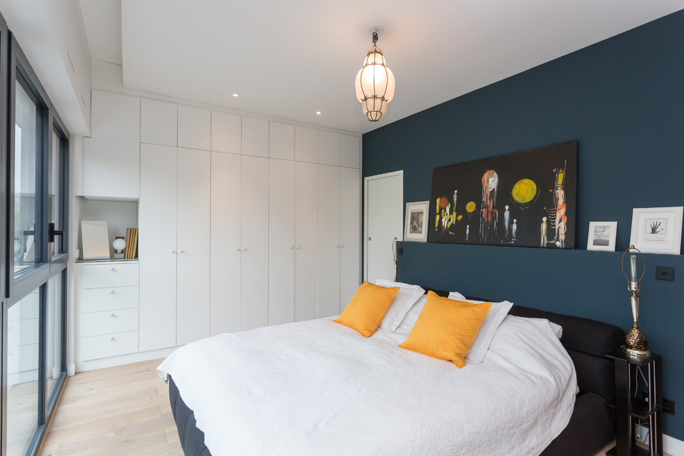Aménagement d'une chambre parentale éclectique de taille moyenne avec parquet clair, aucune cheminée, un sol beige et un mur bleu.
