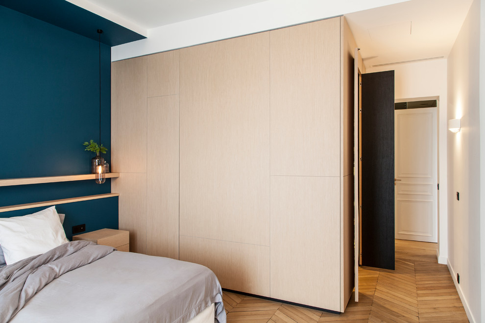 Immagine di una camera matrimoniale minimal di medie dimensioni con pareti blu, pavimento in legno massello medio, nessun camino e pavimento marrone