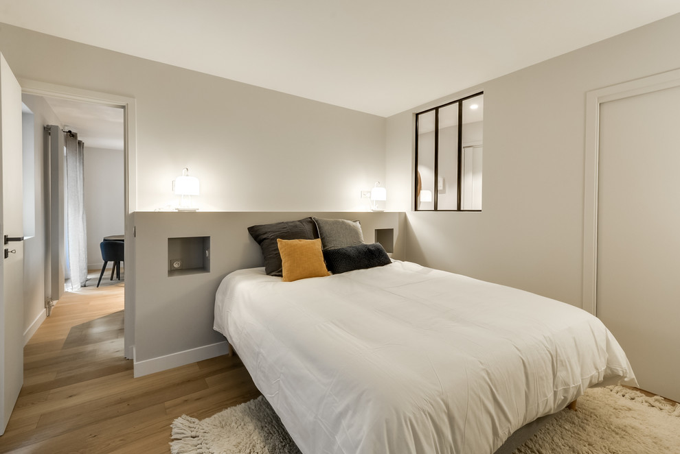 Mittelgroßes Modernes Hauptschlafzimmer ohne Kamin mit grauer Wandfarbe und hellem Holzboden in Paris
