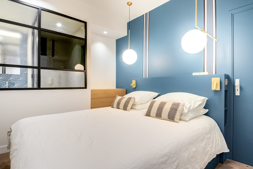 Cette image montre une chambre parentale nordique de taille moyenne avec un mur bleu, parquet foncé et un sol marron.