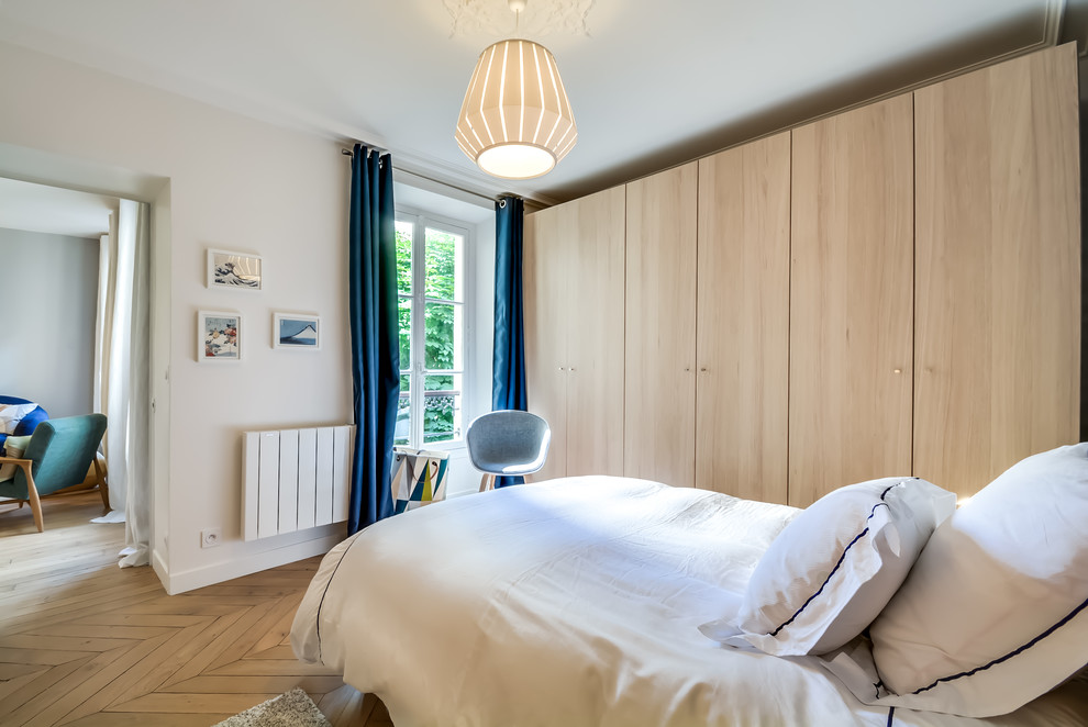 Design ideas for a scandinavian bedroom in Paris with blue walls and light hardwood flooring.