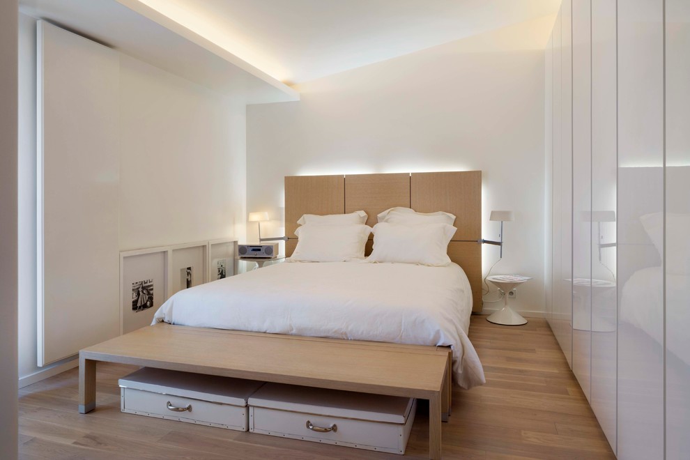 Idéer för att renovera ett litet minimalistiskt huvudsovrum, med vita väggar och ljust trägolv