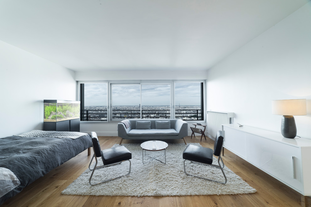Großes Modernes Schlafzimmer ohne Kamin mit weißer Wandfarbe, hellem Holzboden und braunem Boden in Paris