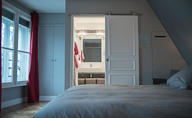 Immagine di una camera da letto design di medie dimensioni con pareti grigie, parquet chiaro e nessun camino