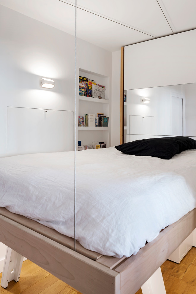 Cette image montre une petite chambre parentale nordique avec un mur blanc et un sol en bois brun.