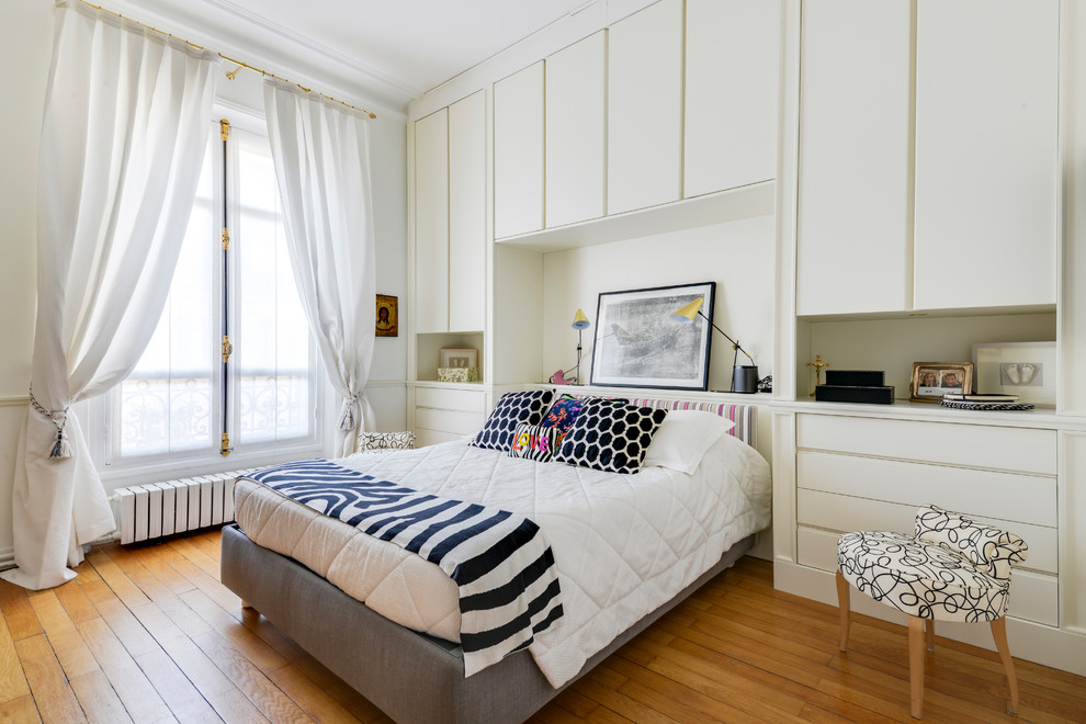 Cette photo montre une chambre parentale tendance de taille moyenne avec un mur blanc, parquet clair, aucune cheminée et un sol beige.