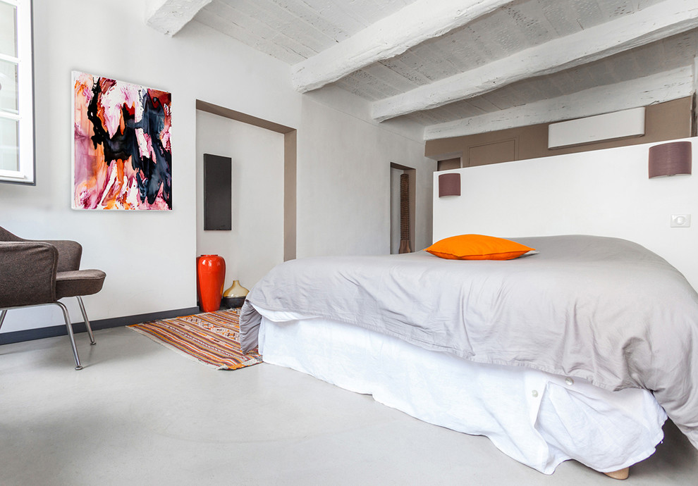 Ejemplo de dormitorio principal contemporáneo de tamaño medio sin chimenea con paredes blancas y suelo de cemento