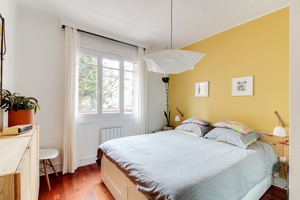 Cette photo montre une chambre tendance avec un mur jaune, parquet foncé et un sol marron.