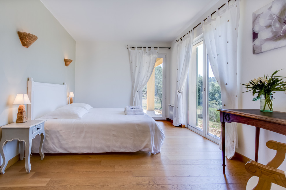 Idée de décoration pour une grand chambre d'amis tradition avec un mur blanc, un sol en bois brun et aucune cheminée.