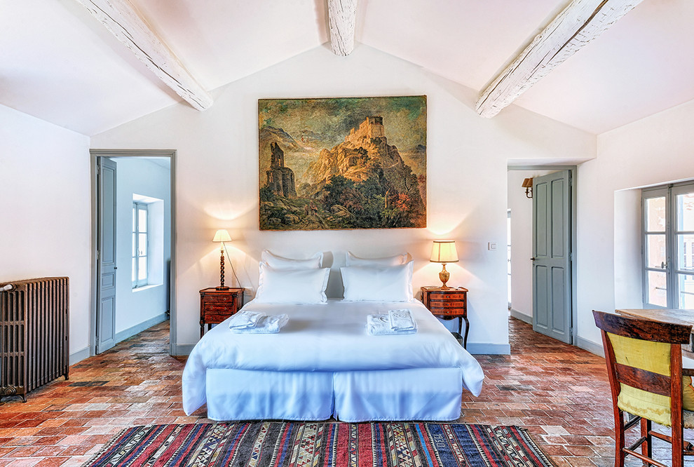 Foto di una camera matrimoniale mediterranea con pareti bianche, pavimento in mattoni e pavimento rosso