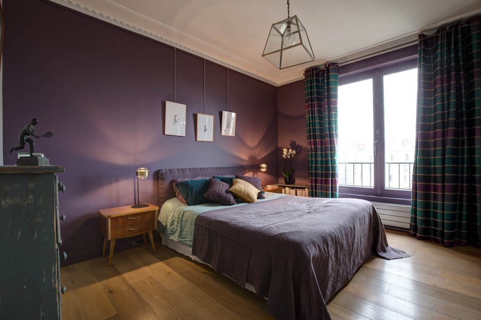 Diseño de dormitorio principal actual de tamaño medio sin chimenea con paredes púrpuras y suelo de madera clara