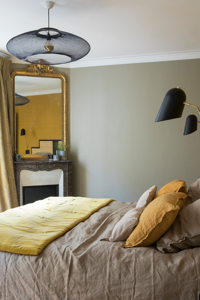 Foto de dormitorio principal actual pequeño con paredes beige, suelo de madera clara, chimenea de esquina, marco de chimenea de piedra y suelo beige