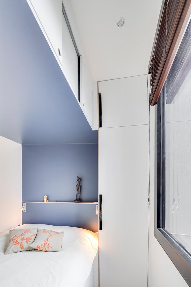 Imagen de dormitorio principal contemporáneo pequeño sin chimenea con paredes azules, suelo de contrachapado y suelo marrón