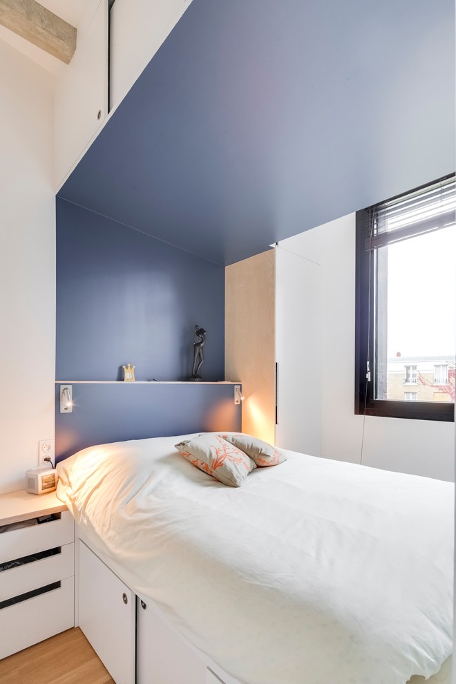 Bild på ett litet funkis huvudsovrum, med blå väggar, plywoodgolv och brunt golv
